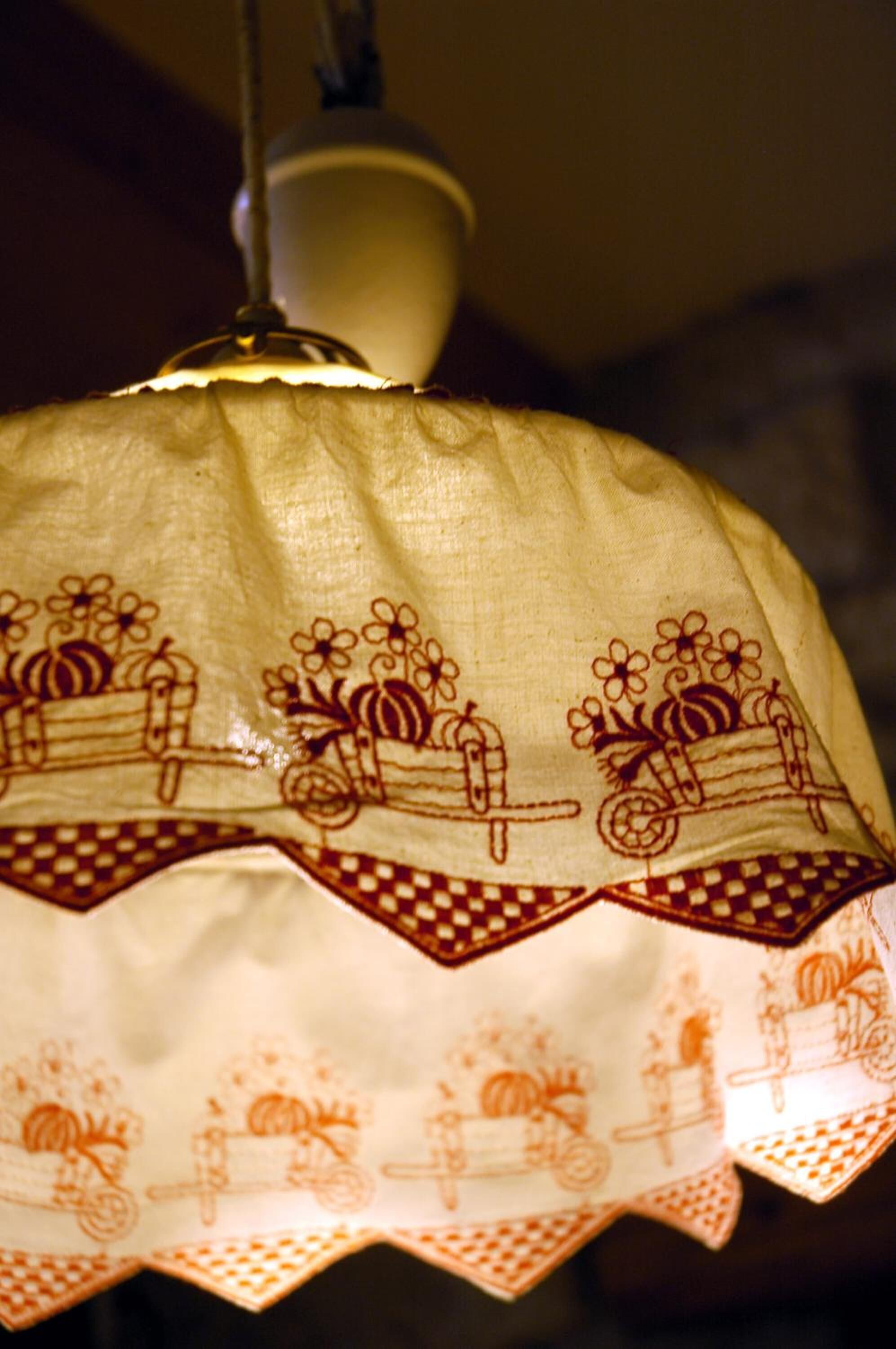 A hanging lamp with a patterned lampshade featuring floral and cart designs.