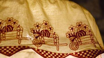 A hanging lamp with a patterned lampshade featuring floral and cart designs.