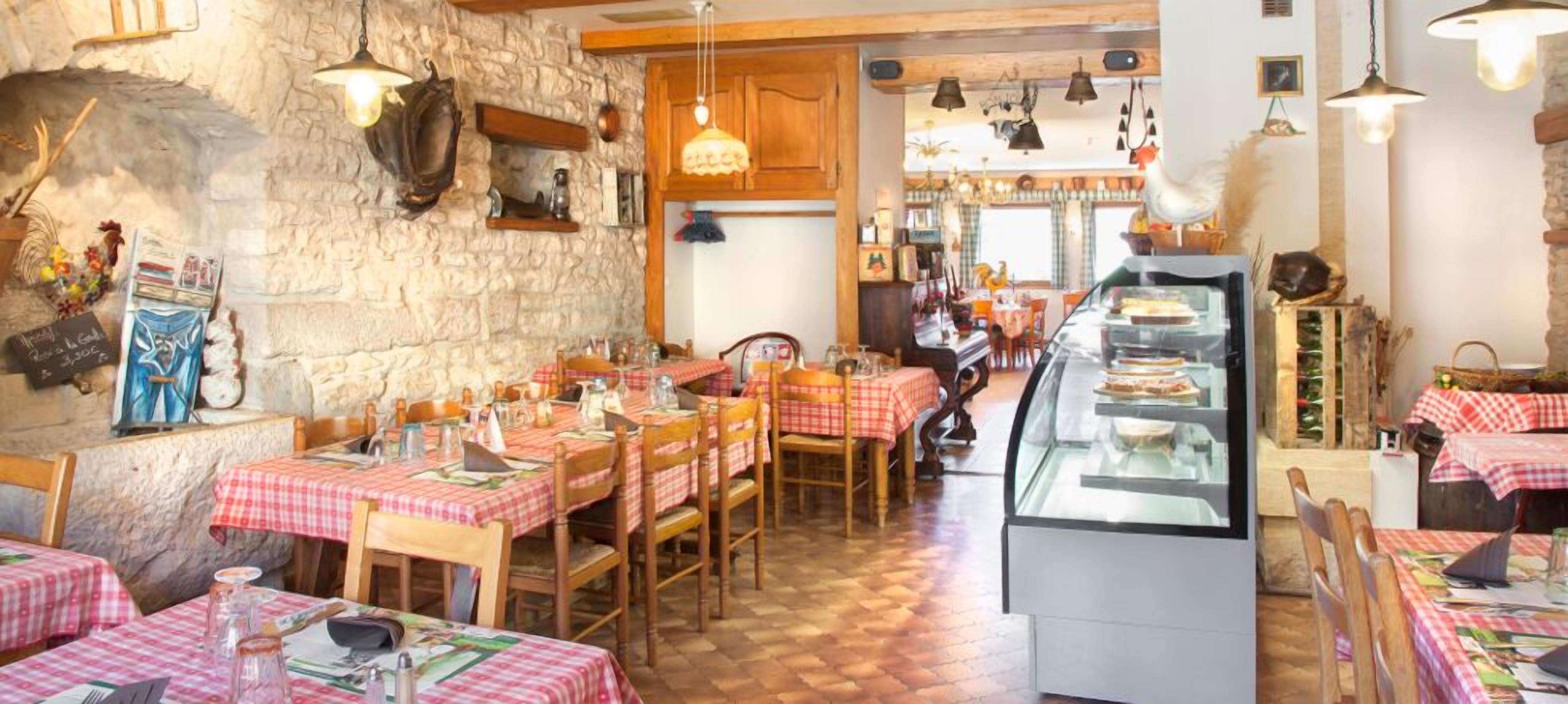 A restaurant with stone walls, wooden furniture, and red and white checkered tablecloths.