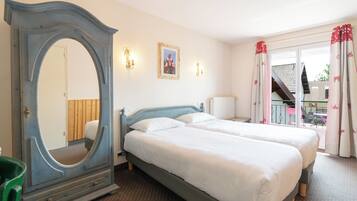 A hotel room with two beds, a large mirror, wall sconces, and a view of the outside balcony.