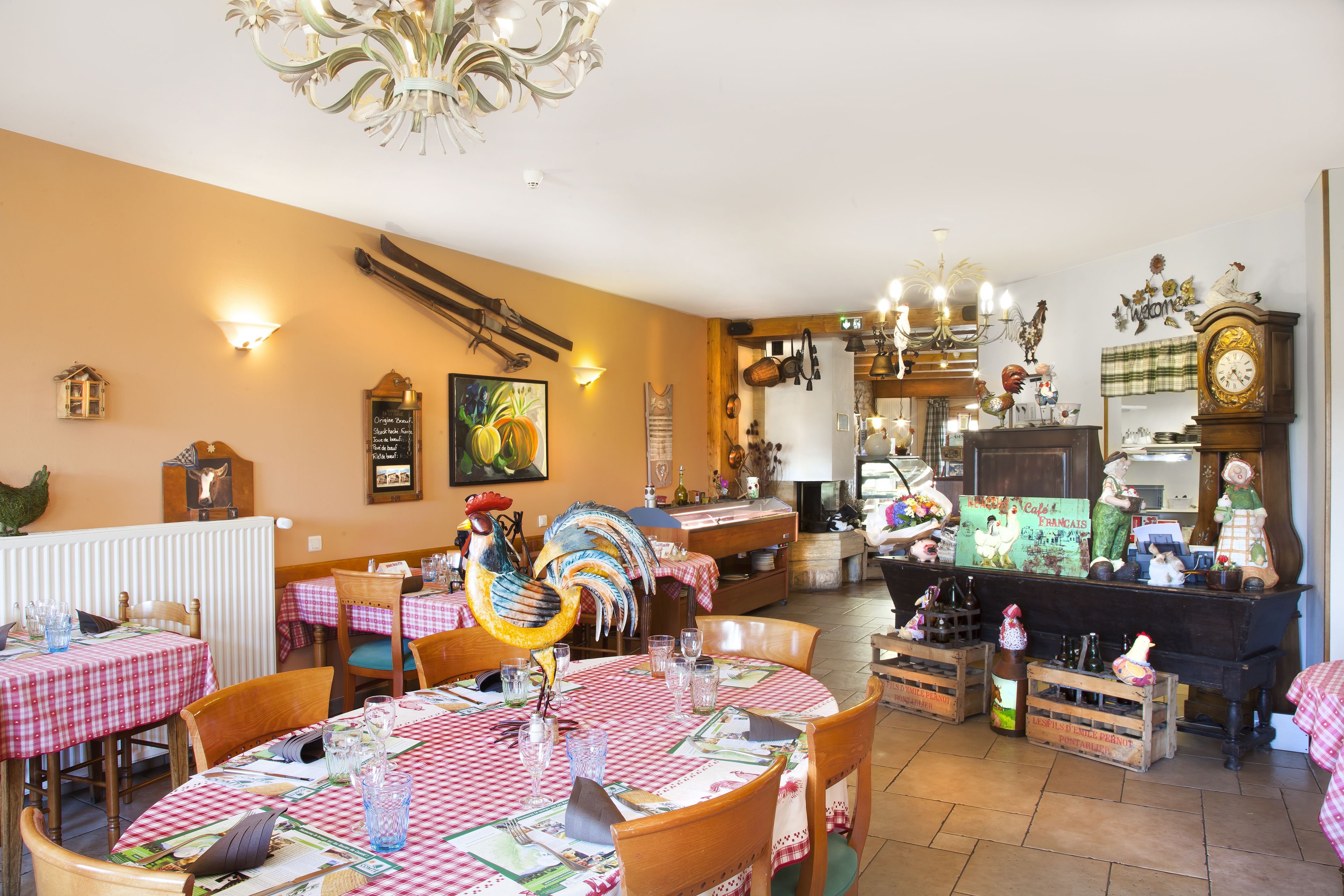 En restaurant med skakternet dug, træstole og en stor dekoration af en hanekylling.
