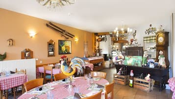 En restaurant med skakternet dug, træstole og en stor dekoration af en hanekylling.