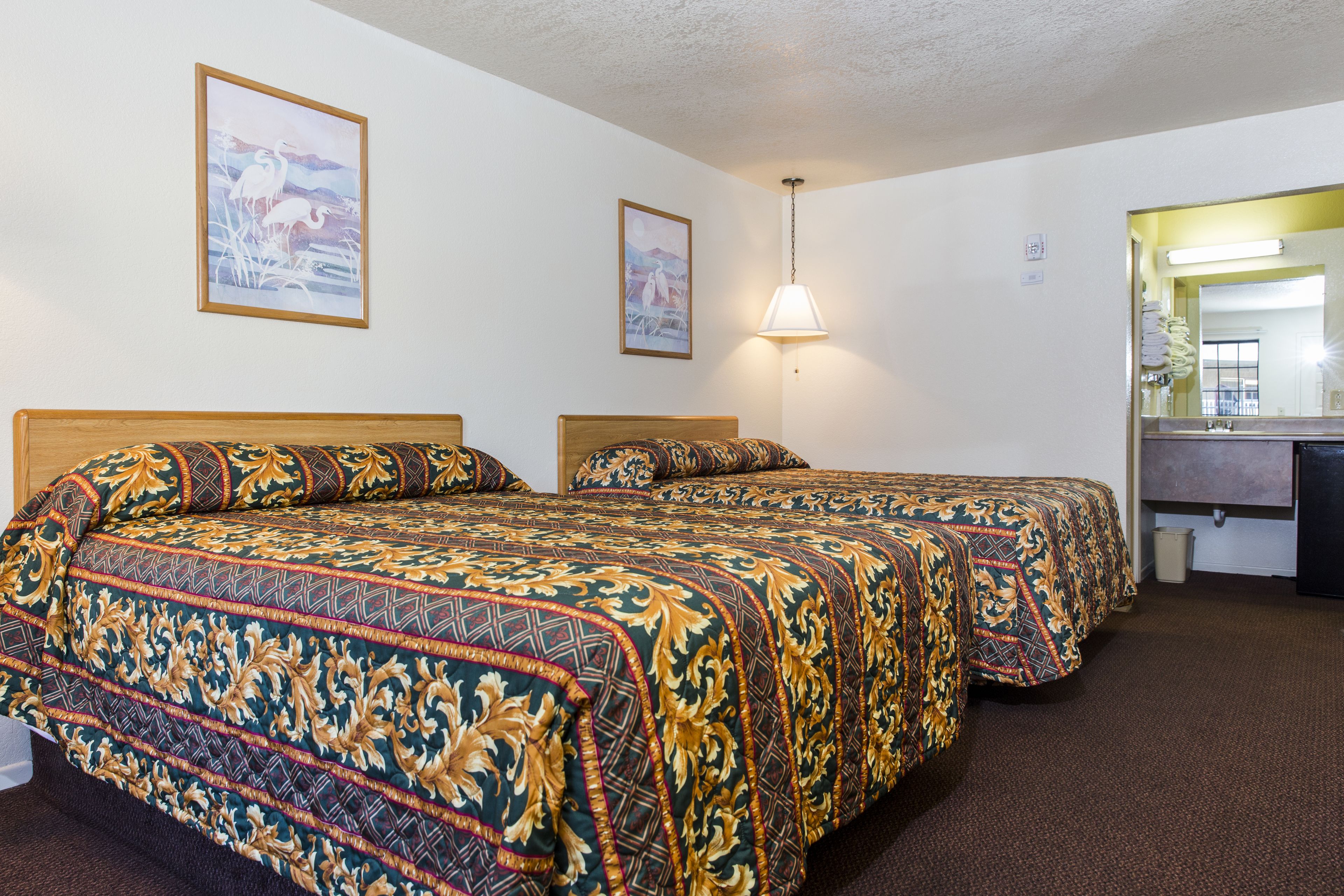Une chambre d’hôtel avec deux lits, un bureau et un miroir.