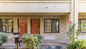 A building with two doors, a mailbox, and a small garden area with bushes and a flower. - Premier Inns Thousand Oaks (Thousand Oaks)