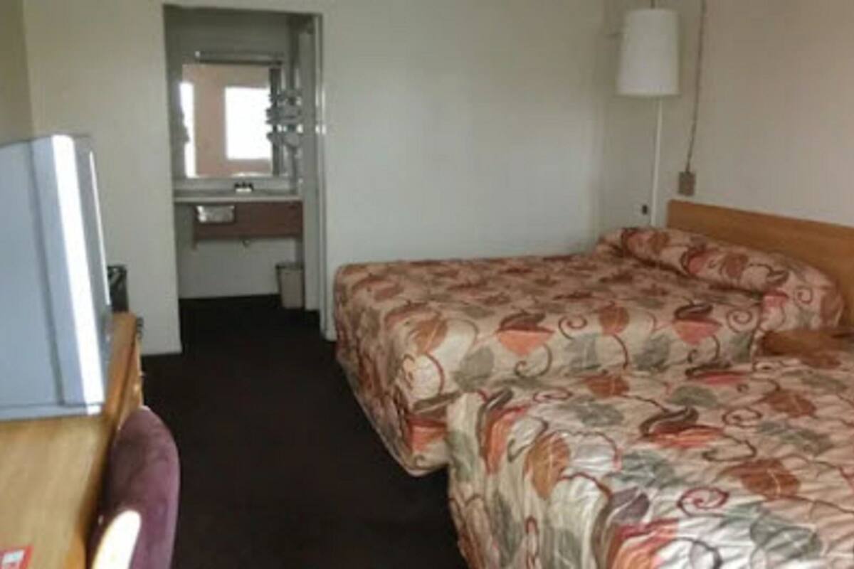 A hotel room with a bed, a desk, and a mirror.