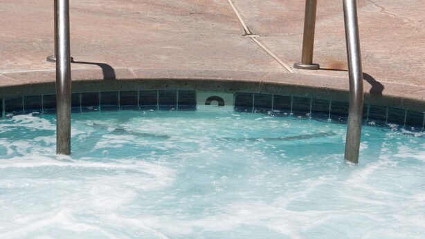 A swimming pool with two white lounge chairs and metal pool ladders. - Premier Inns Thousand Oaks (Thousand Oaks)