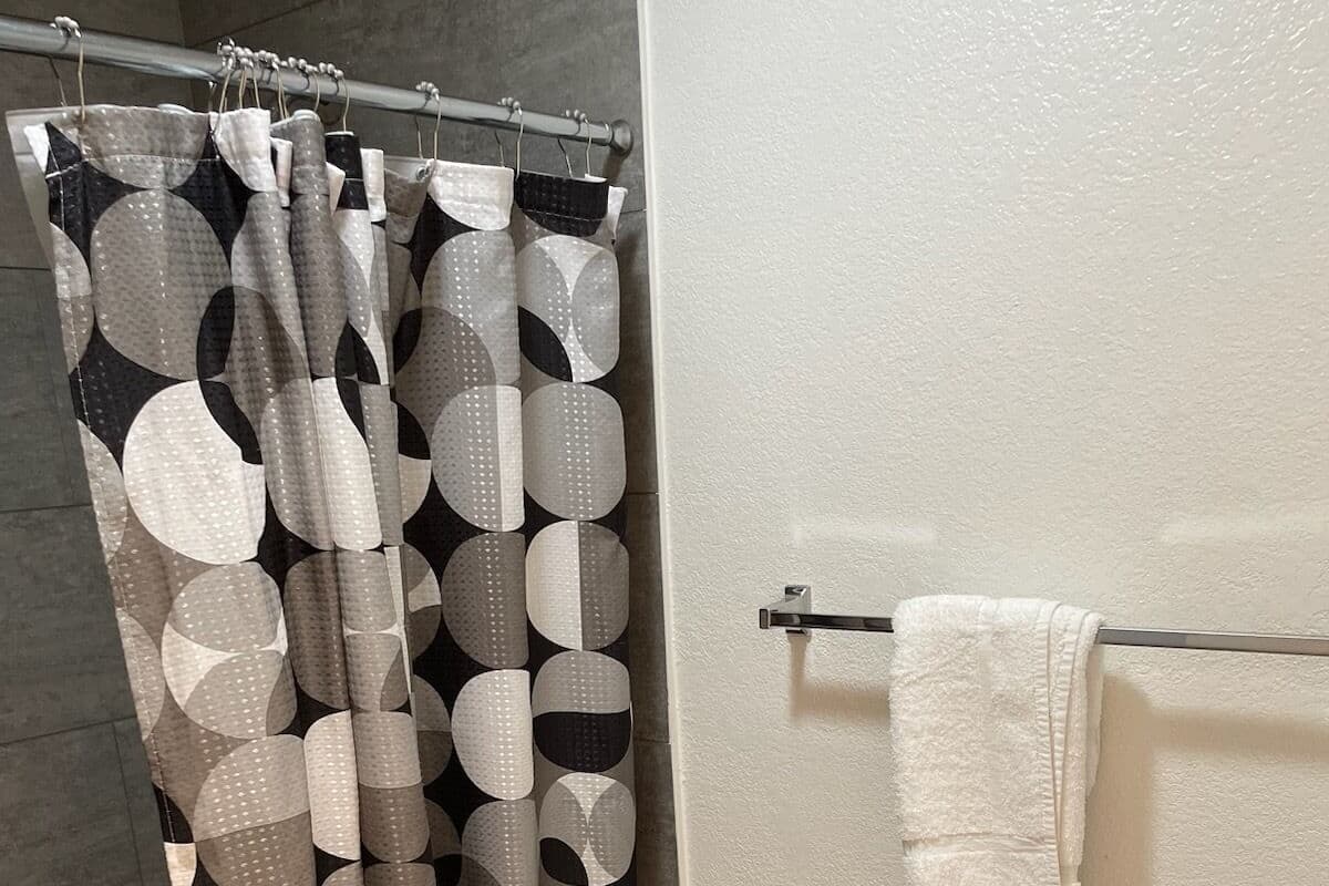 A bathroom with a shower curtain featuring a geometric pattern, a toilet, and a towel rack with a white towel.