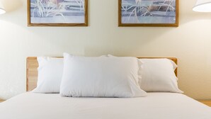 A neatly made bed with white linens and pillows, framed by a wooden headboard. - Premier Inns Thousand Oaks (Thousand Oaks)