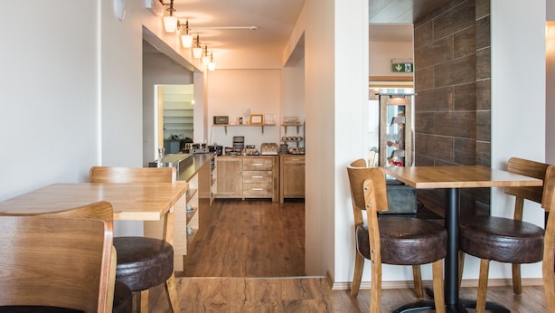Una cocina moderna con armarios de madera, una isla central y una zona de comedor con mesas y sillas de madera.