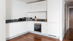 A modern kitchen with white cabinets, a built-in oven, a microwave, and a coffee maker. - Birmingham Serviced Apartments Hagley Rd (Birmingham)