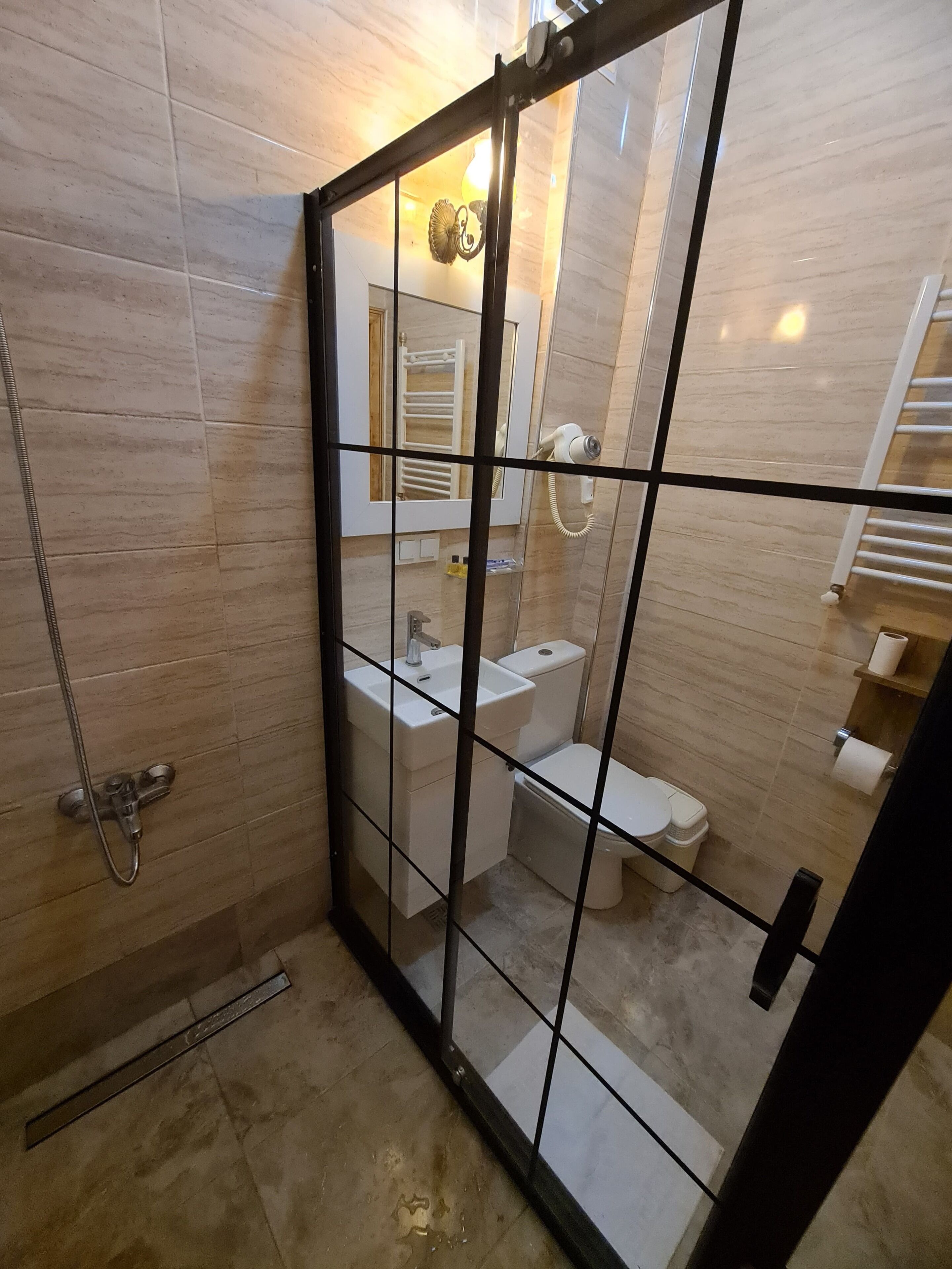 A bathroom with a glass partition, a shower, a toilet, and a sink.