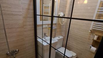 A bathroom with a glass partition, a shower, a toilet, and a sink.