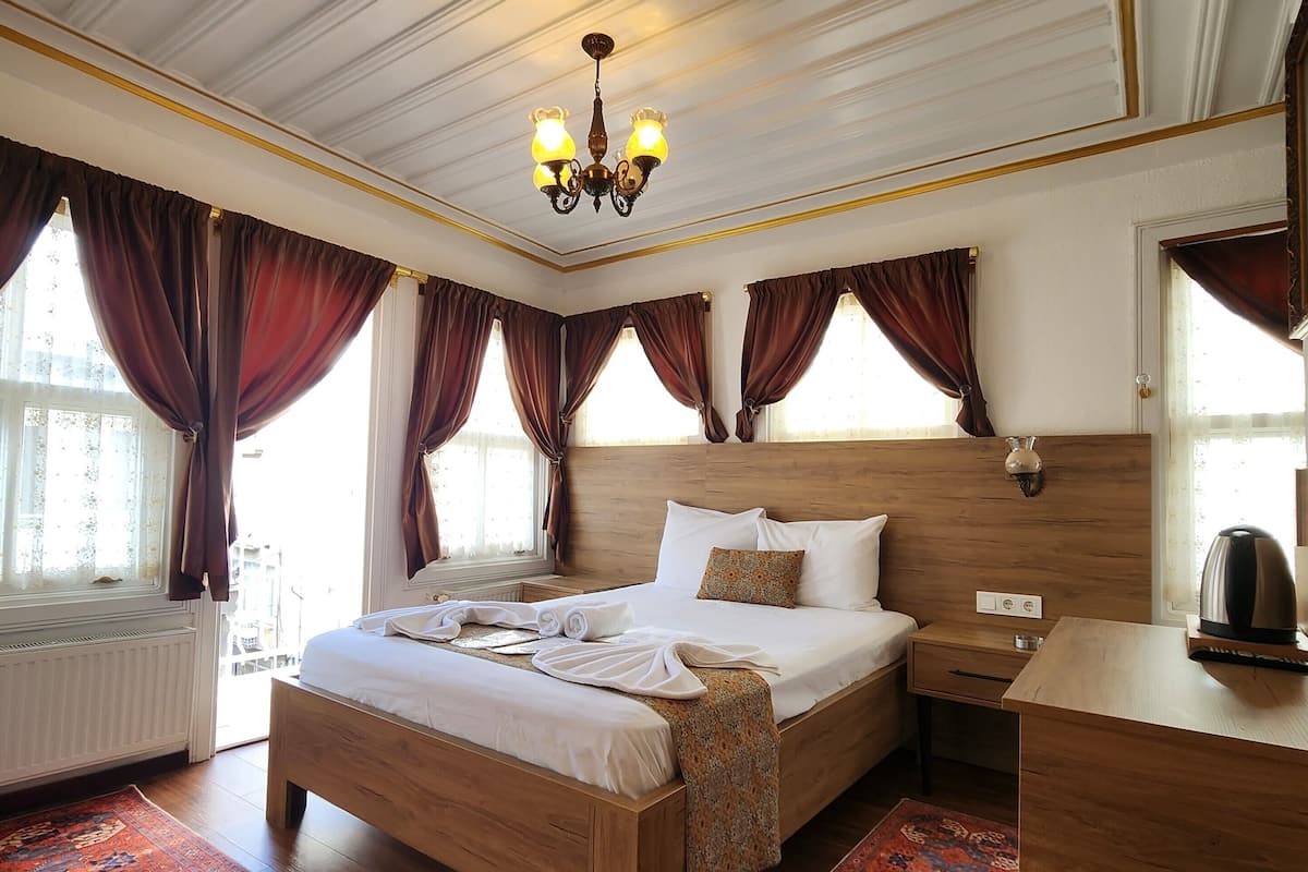 A well-appointed bedroom with a large bed, a wooden nightstand, a desk, and a chandelier.