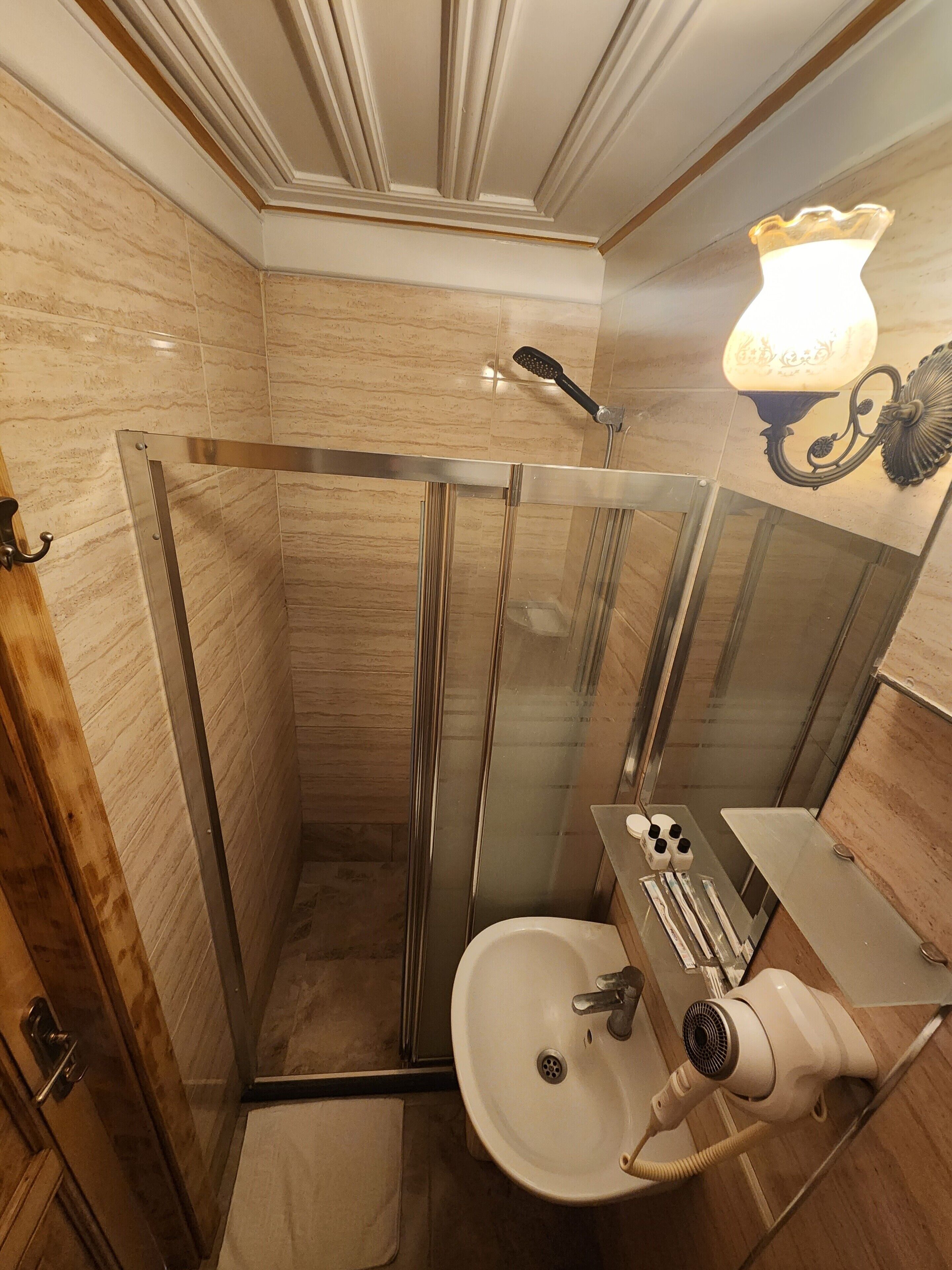 Un baño con ducha de vidrio, lavamanos y secador de pelo.