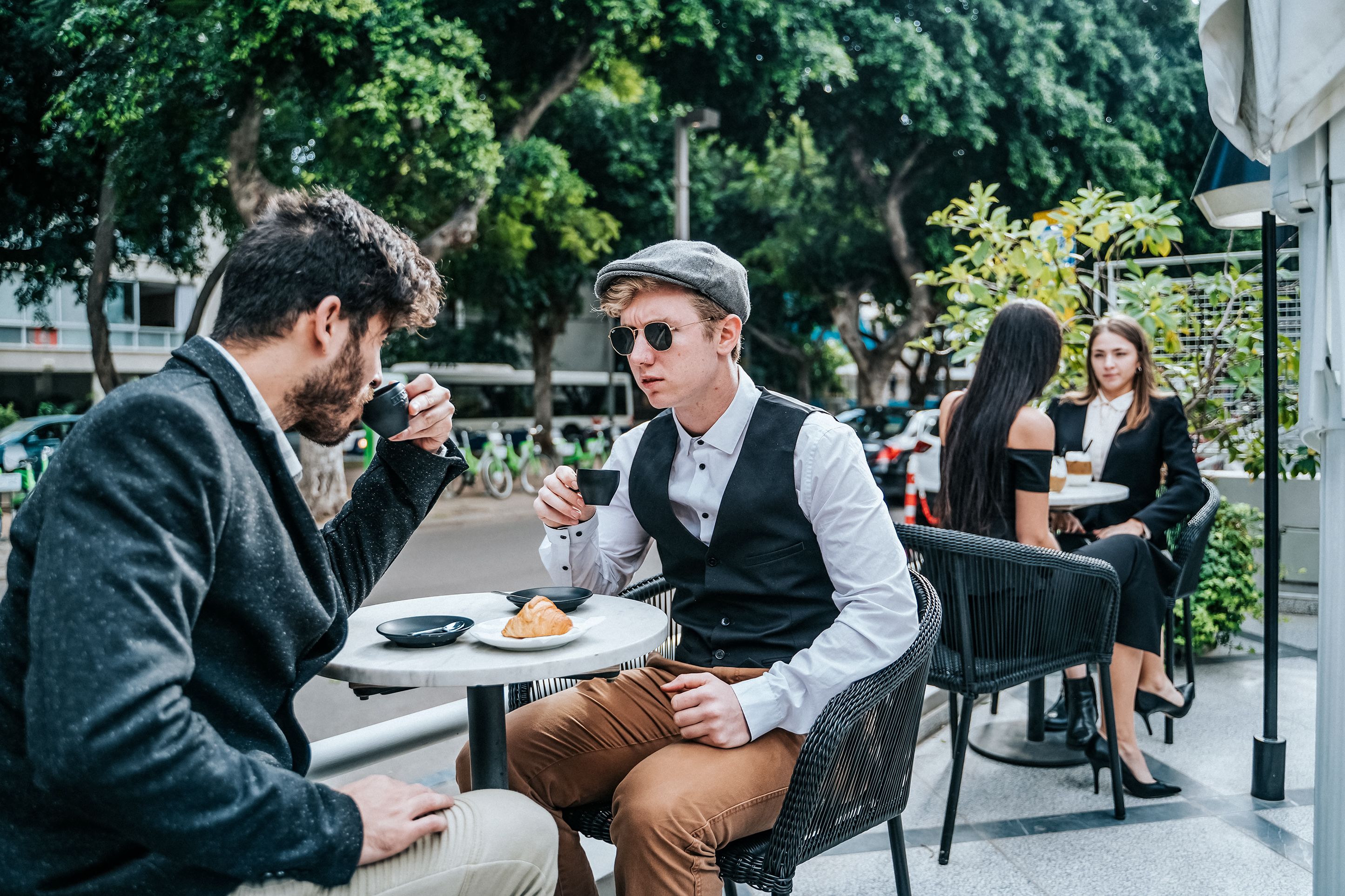 Un café avec une terrasse, une table ronde et une personne tenant une tasse.