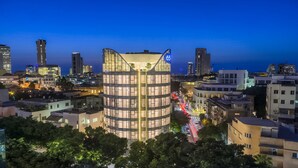 A modern building with a curved facade, surrounded by other urban structures. - 65 Hotel, Rothschild Tel Aviv - an Atlas Boutique Hotel (Tel Aviv)