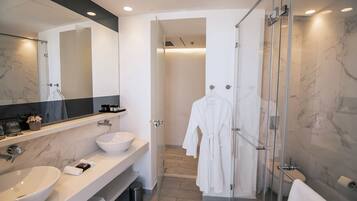 A modern bathroom with two sinks, a large mirror, and a glass shower enclosure.