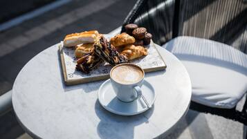 A round table with a white cup of coffee and a plate of pastries.