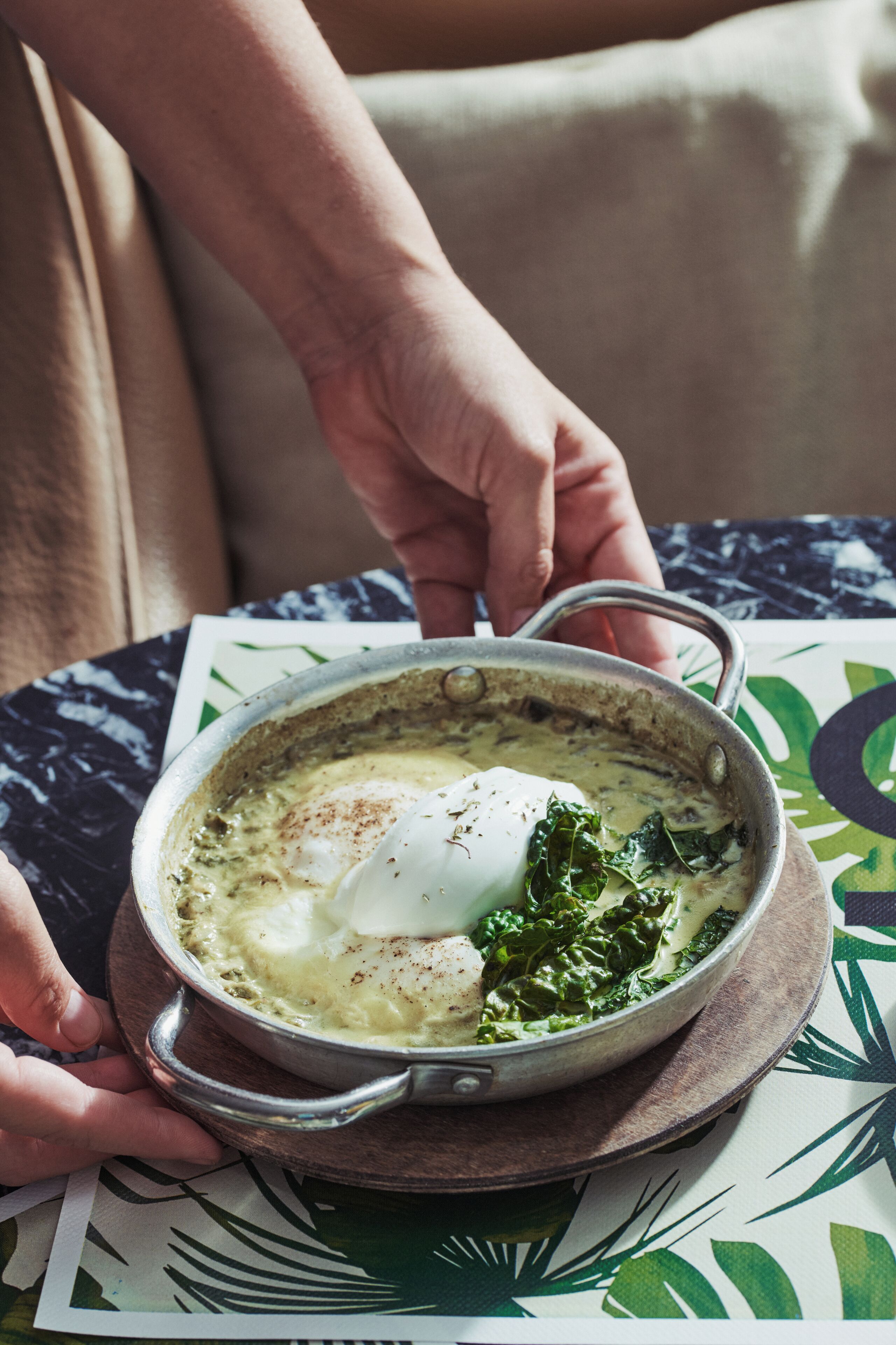 Una persona sosteniendo un tazón de sopa con un huevo escalfado y vegetales verdes.