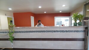 A reception desk with a tiled floor, a potted plant, and a window with a view of the outside.