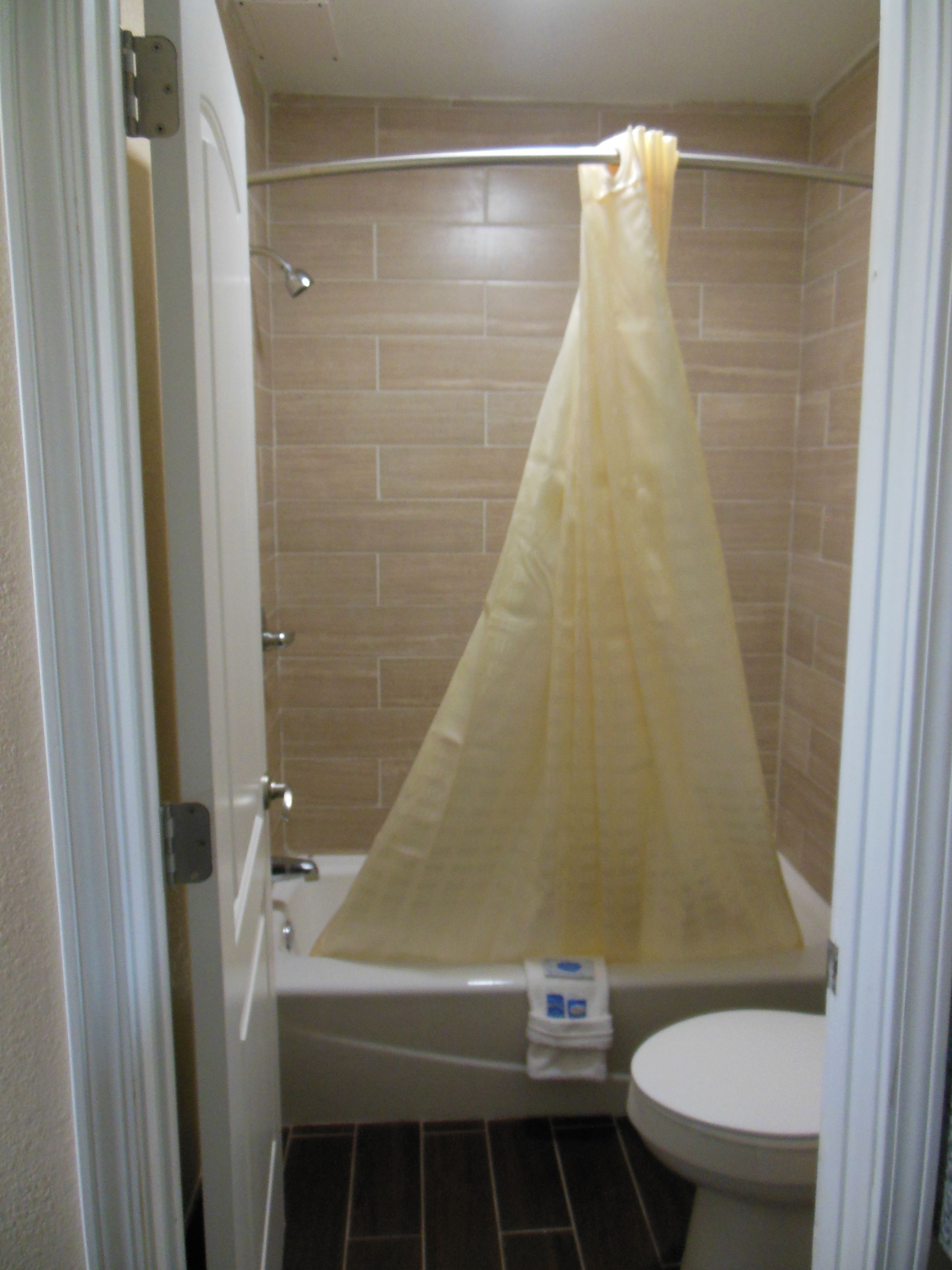 A bathroom with a shower curtain, a bathtub, and a toilet.