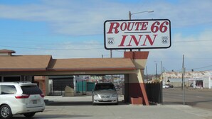 A Route 66 Inn sign with a clear view of the building's entrance and a parking area.