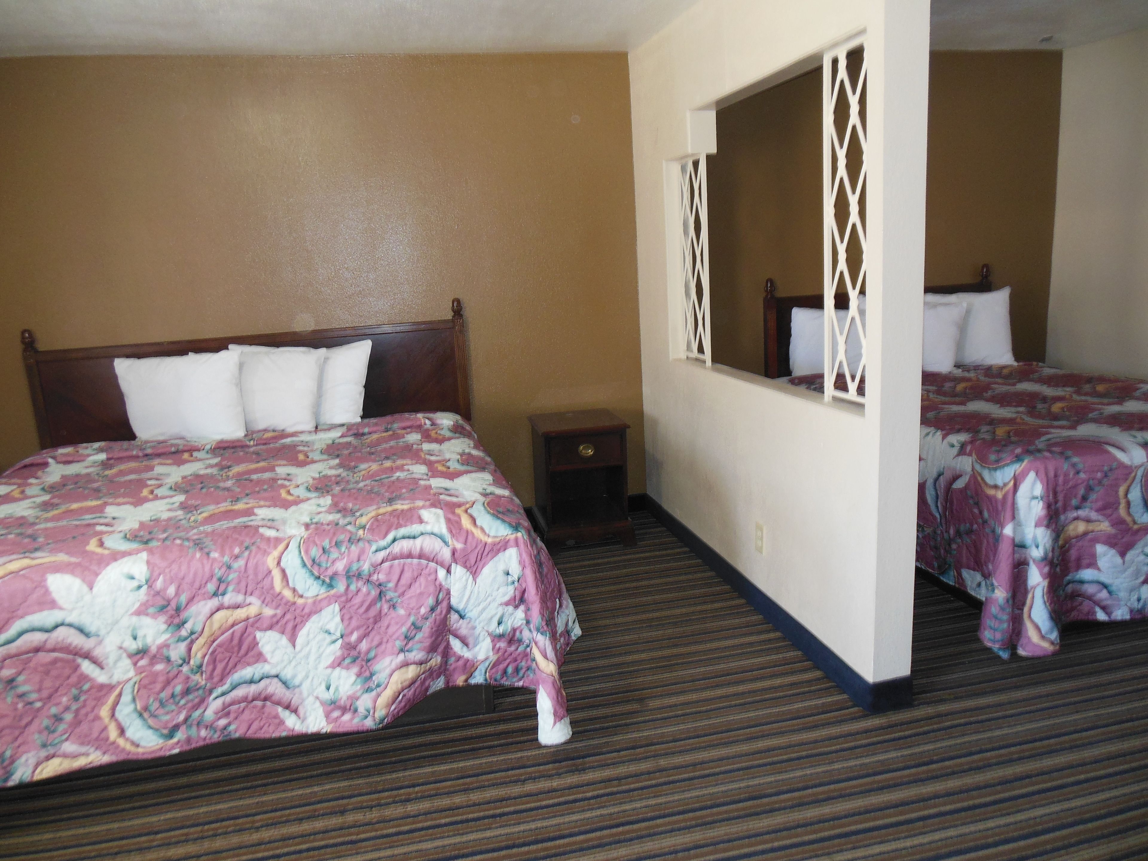 Een hotelkamer met een groot bed, een nachtkastje, een spiegel en een vloerbedekking.