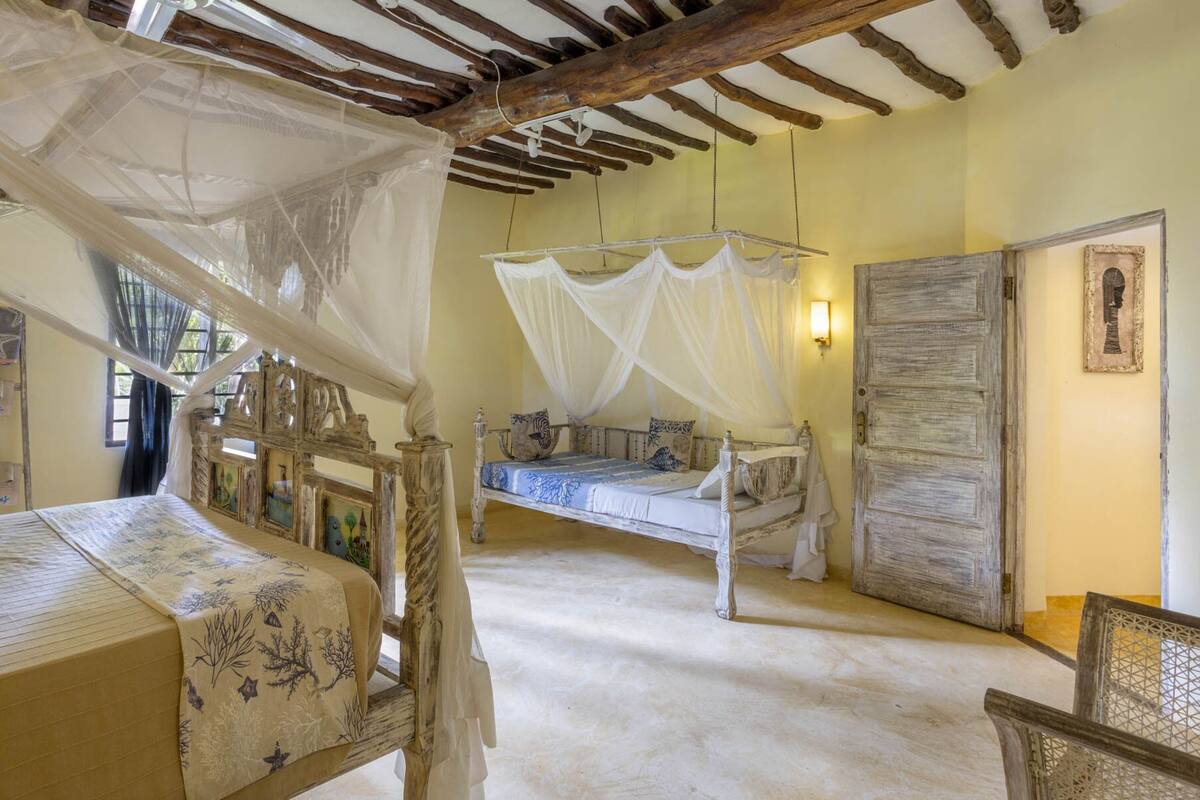 Quarto rústico com cama de dossel, uma cama separada com dossel, e uma grande porta de madeira.