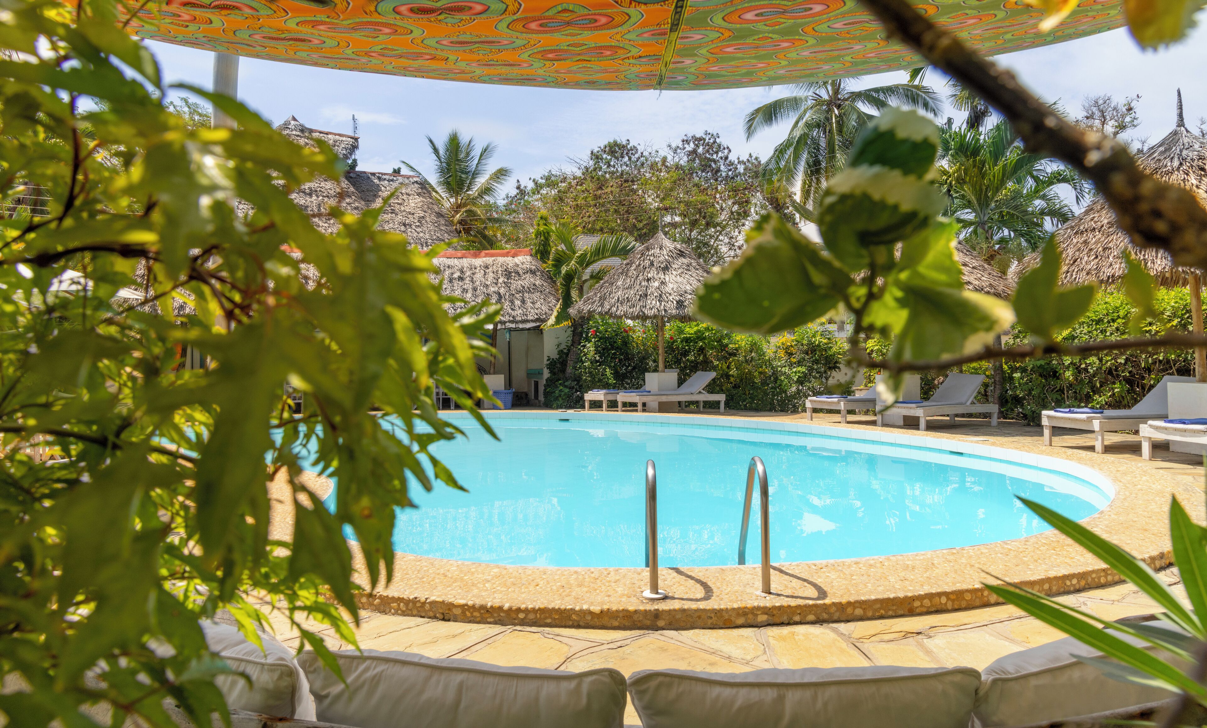 A pool area with lounge chairs and a thatched-roof structure.
