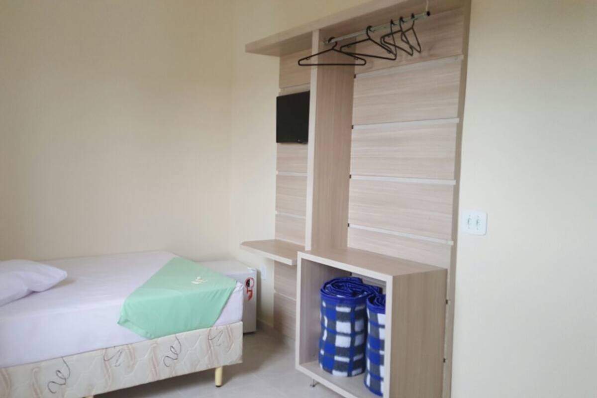 Un dormitorio con cama, armario y estantería con cajas de almacenamiento.