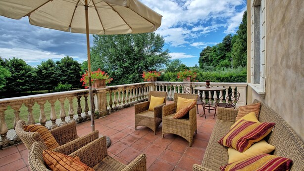 A terrace with wicker furniture, a table, and potted plants. - Villa Fiamma (Capannori)
