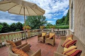 A terrace with wicker furniture, a table, and potted plants. - Villa Fiamma (Capannori)