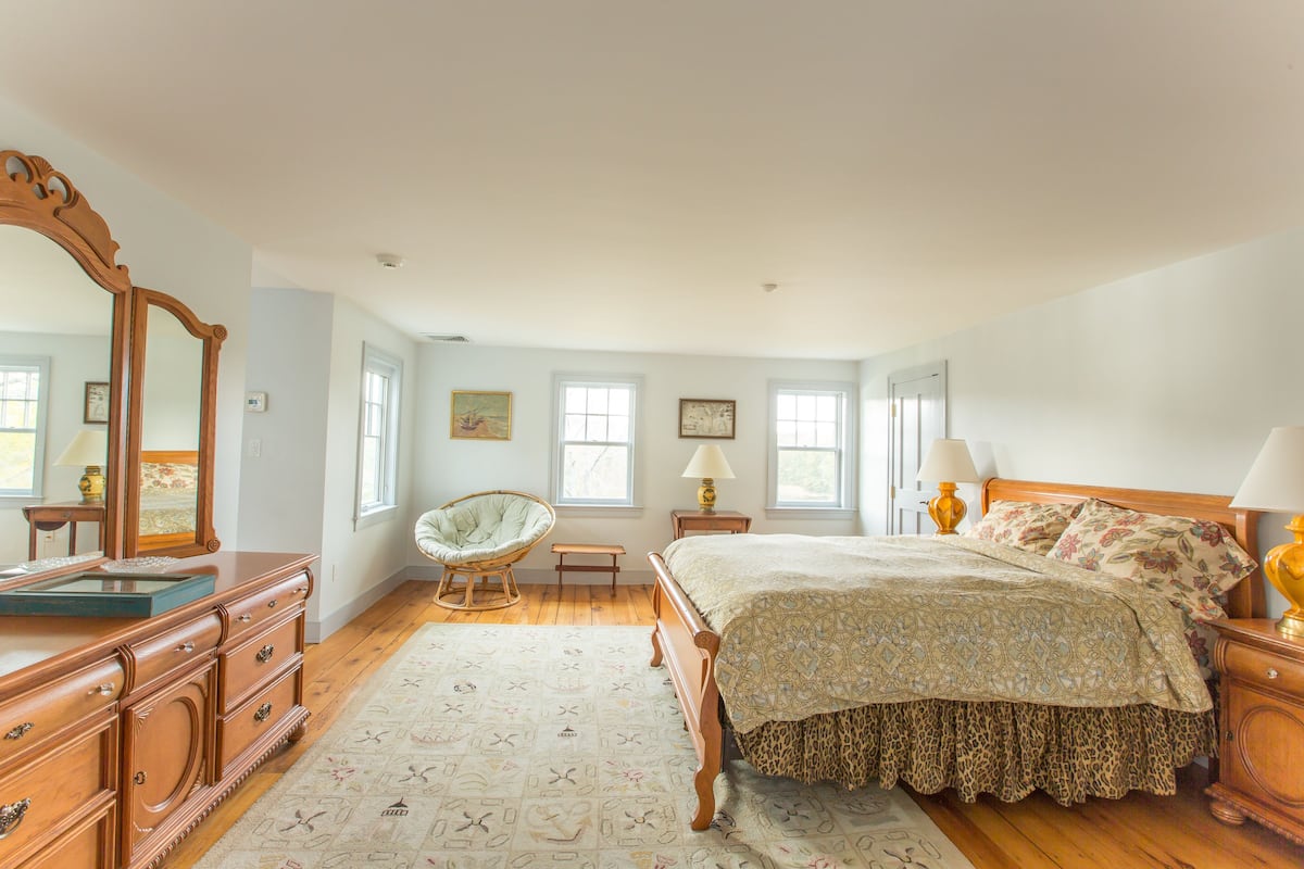 Un dormitorio con una cama de madera, un aparador, una silla y un espejo grande.