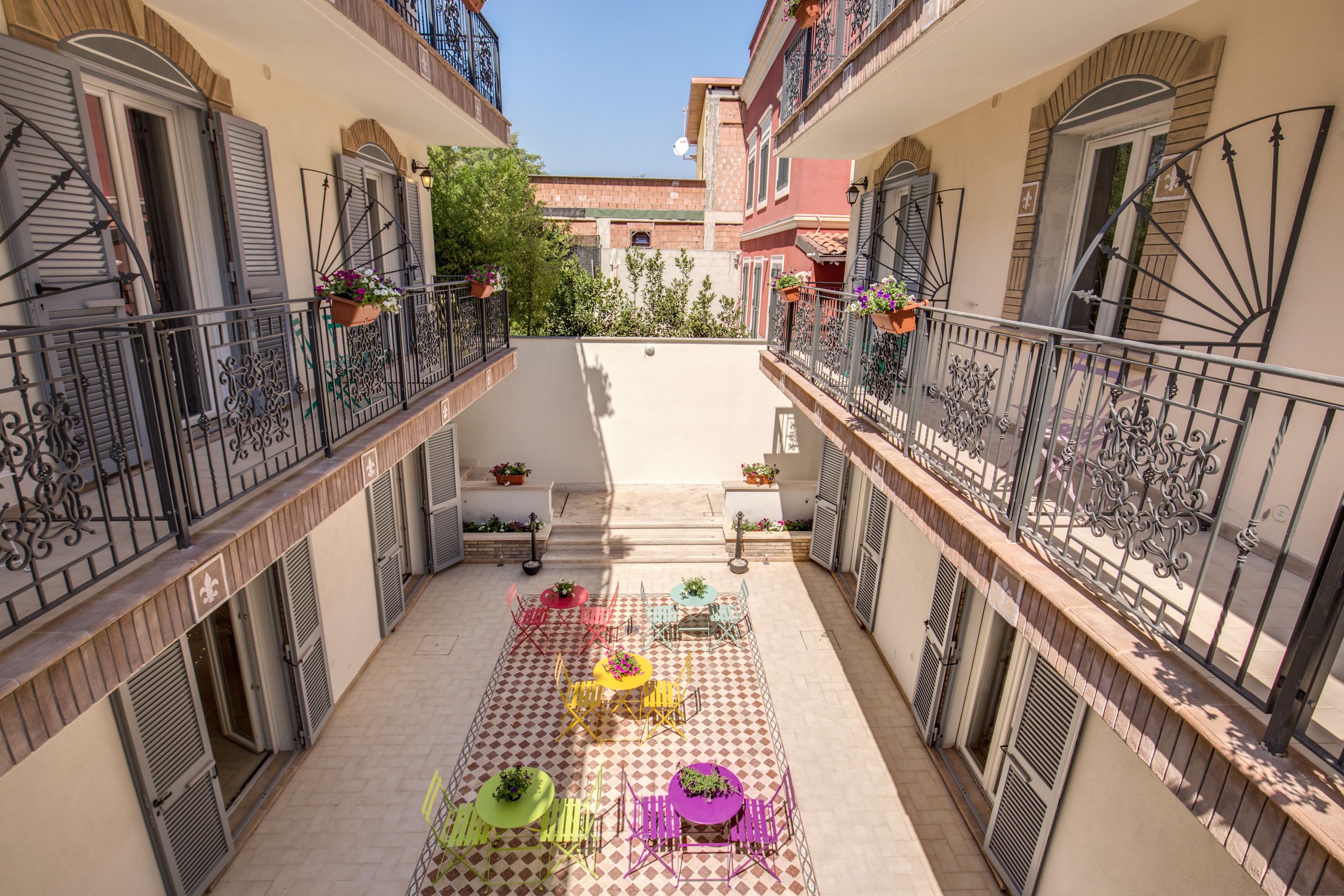 A courtyard with a checkered floor, outdoor seating, and balconies with metal railings.