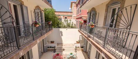 A courtyard with a checkered floor, outdoor seating, and balconies with metal railings.