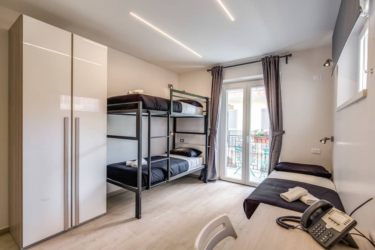 A dormitory room with bunk beds, a desk with a phone, and a sliding door closet.