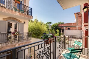 A balcony with a wrought iron railing, a green bench, and potted plants. - The Bricks Rome (Rome)