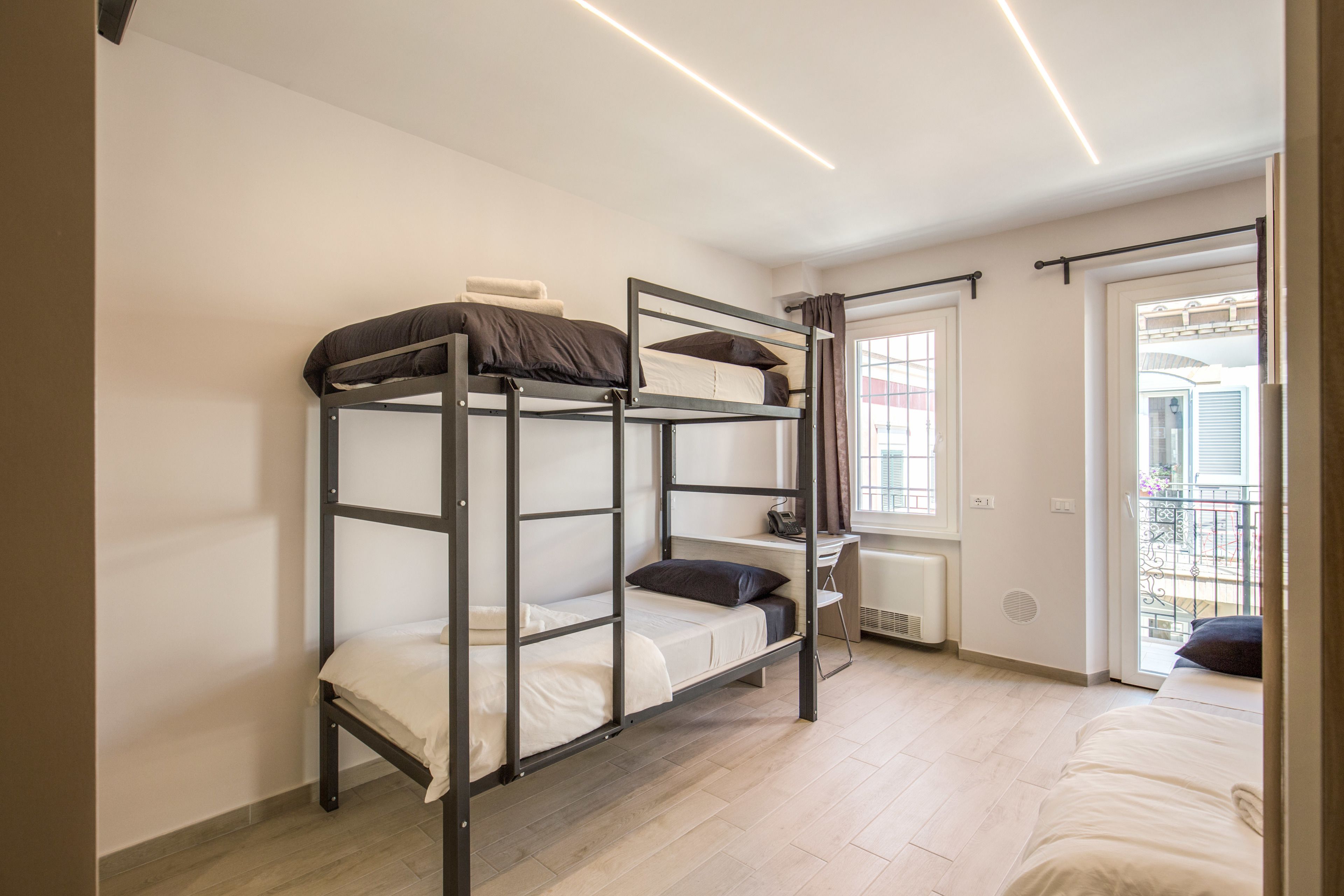 Un dormitorio con literas, un escritorio y una ventana con cortinas.