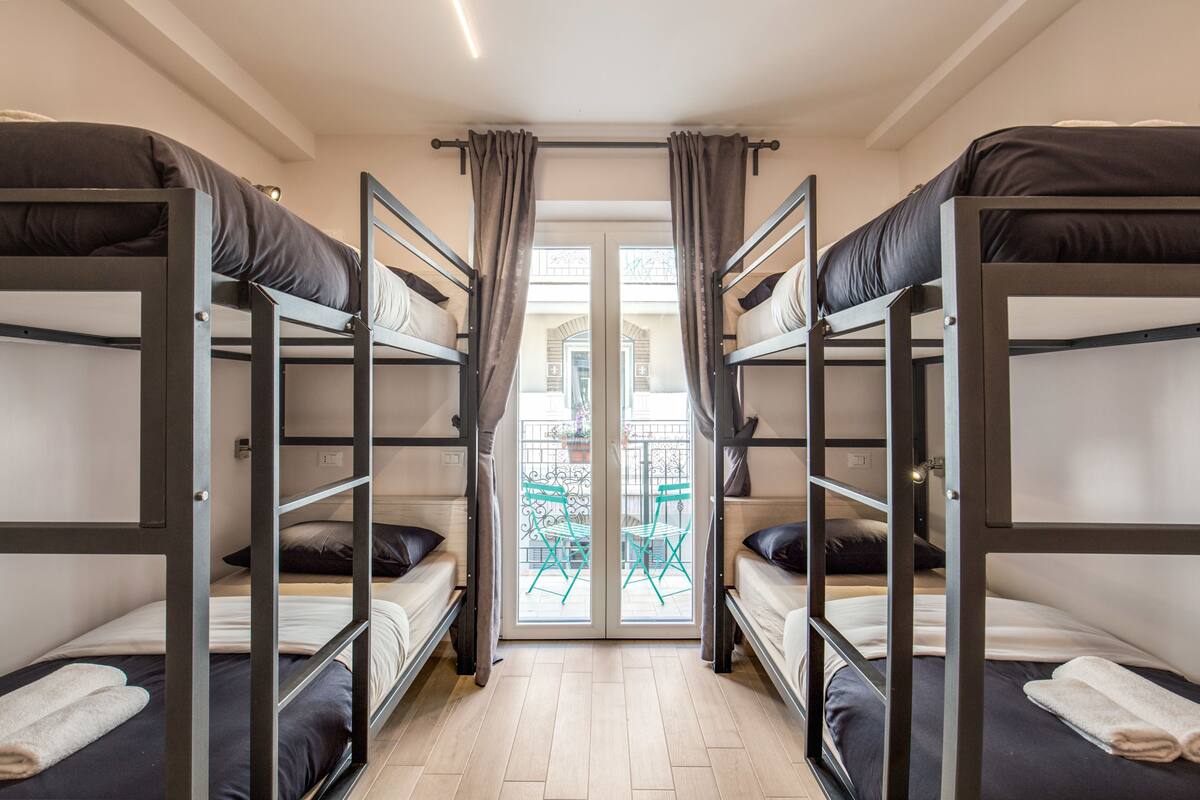 A room with bunk beds, a door leading to an outdoor area, and a small table with chairs.