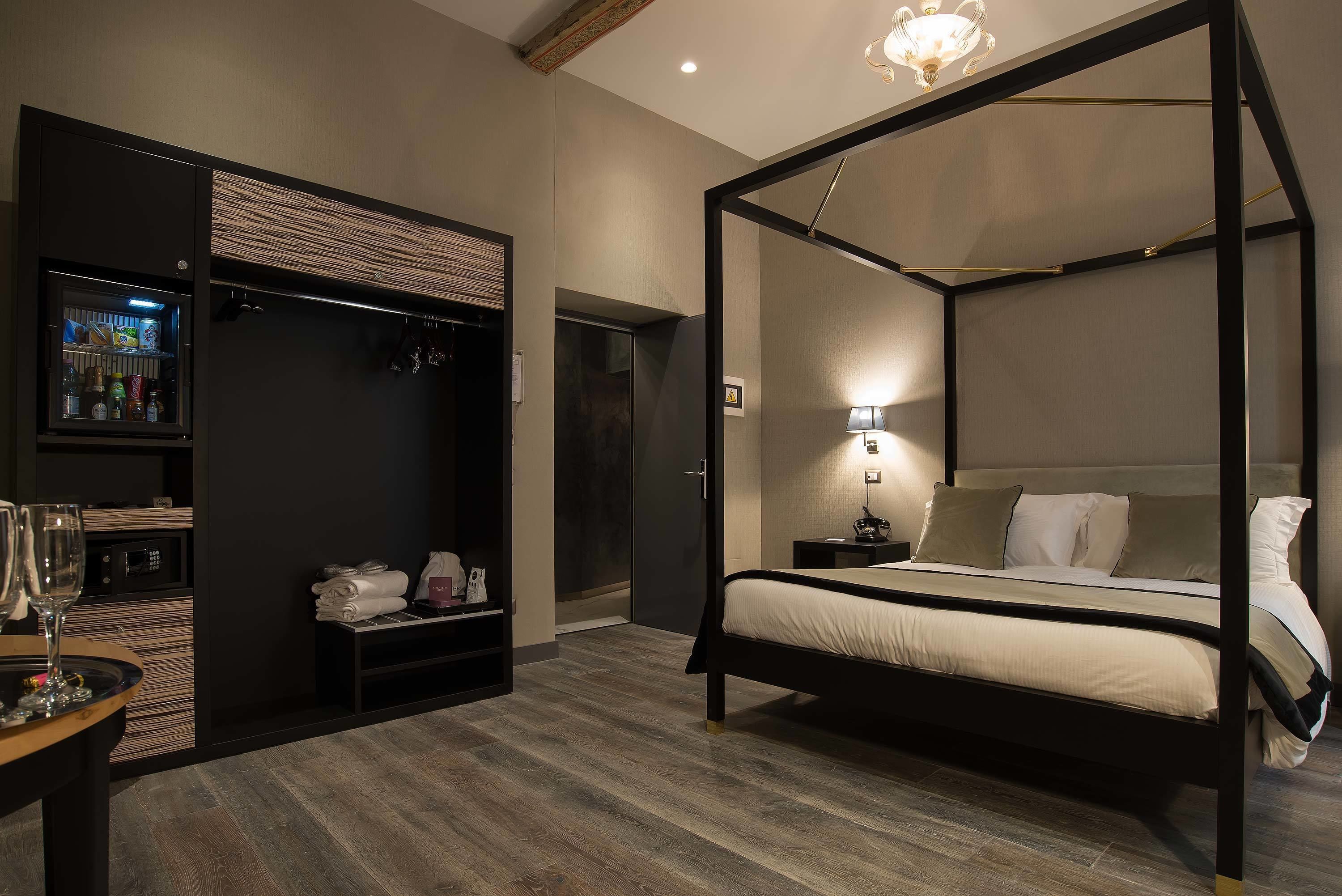 A modern bedroom with a four-poster bed, a walk-in closet, and a minibar.