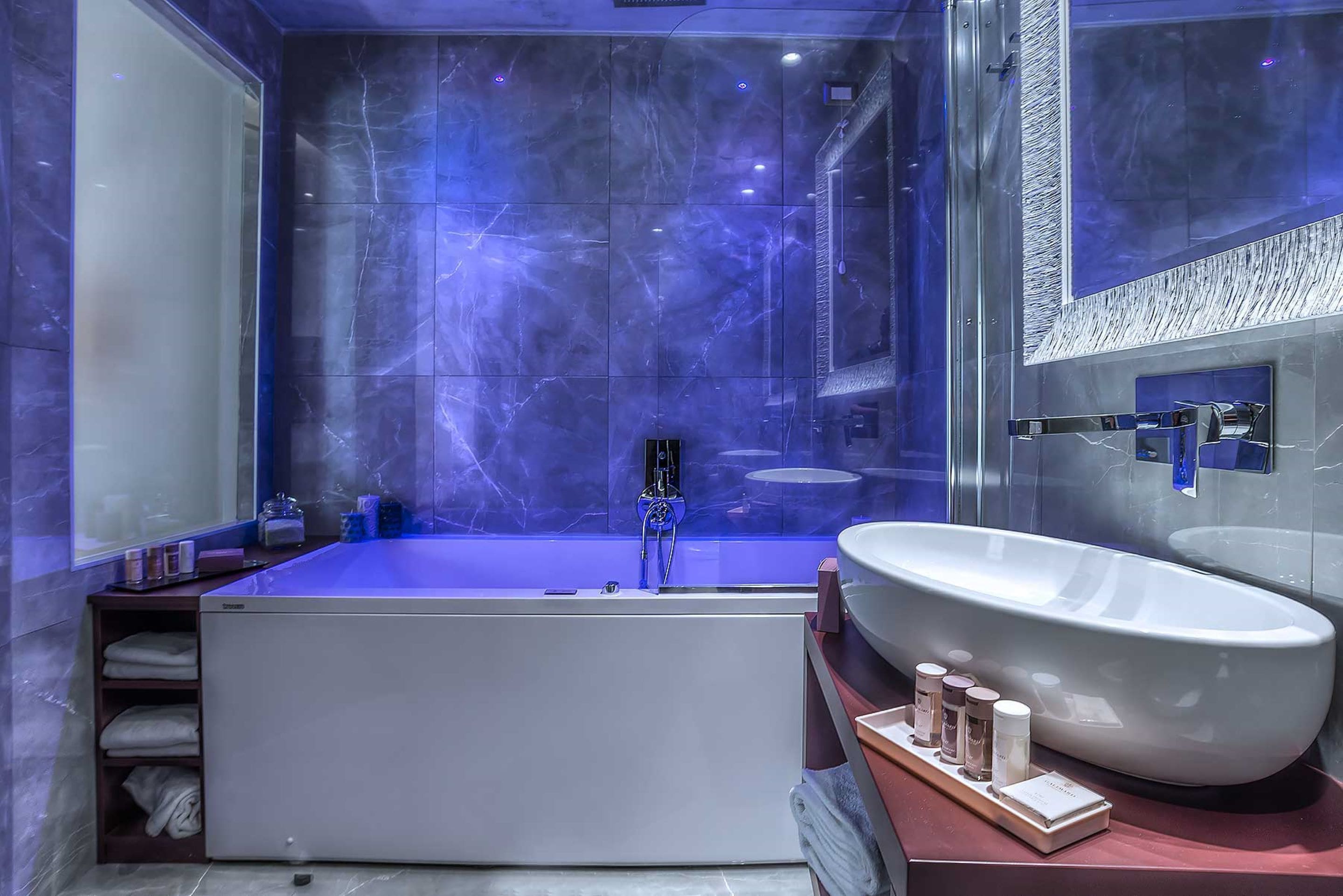 Un bagno moderno con una vasca da bagno ampia, un lavabo sospeso e un box doccia in vetro.