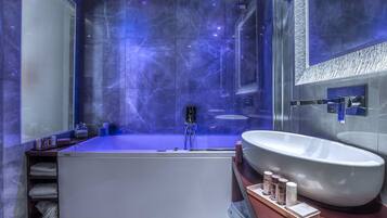 Un bagno moderno con una vasca da bagno ampia, un lavabo sospeso e un box doccia in vetro.