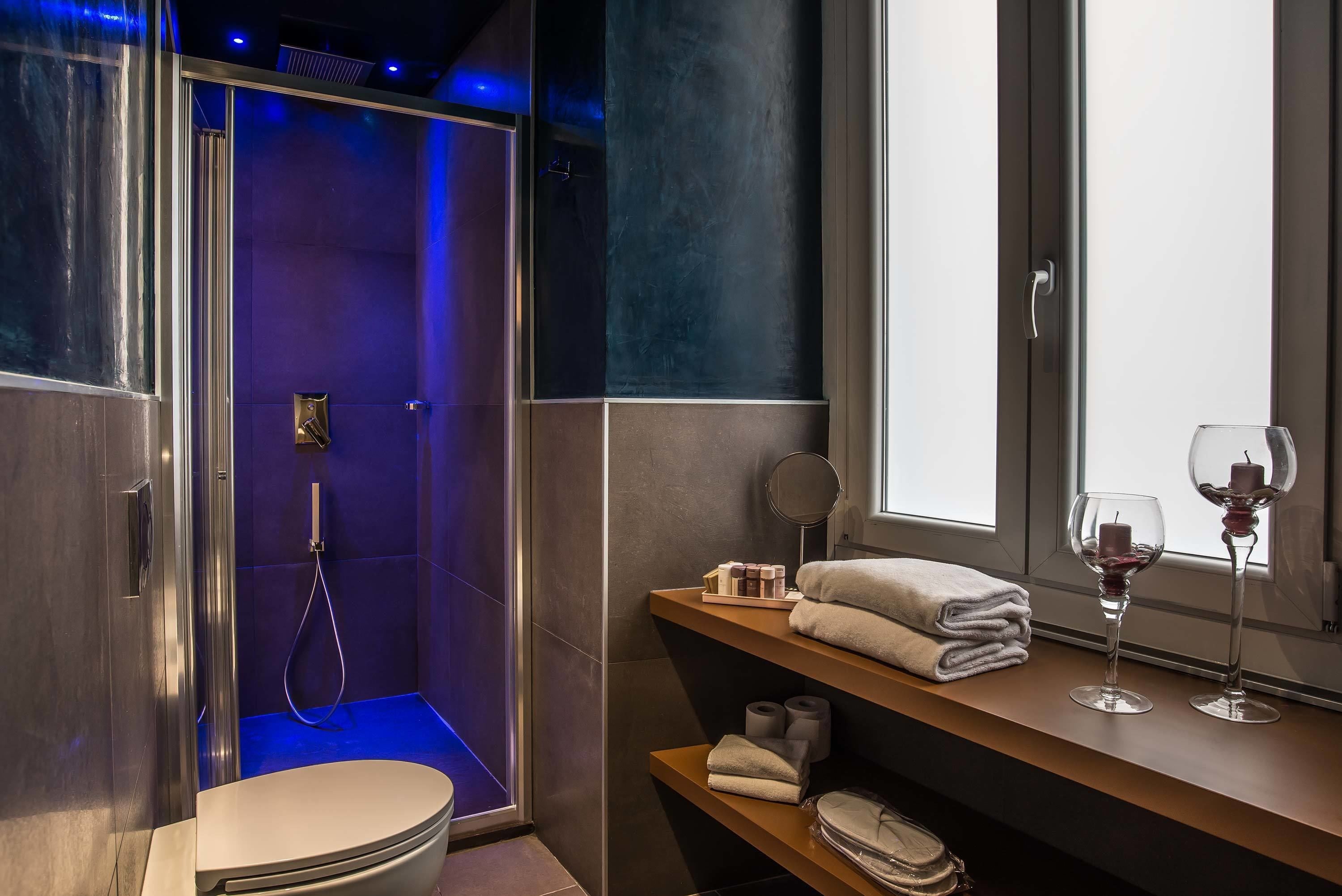 A modern bathroom with a shower, toilet, and vanity with towels and toiletries.