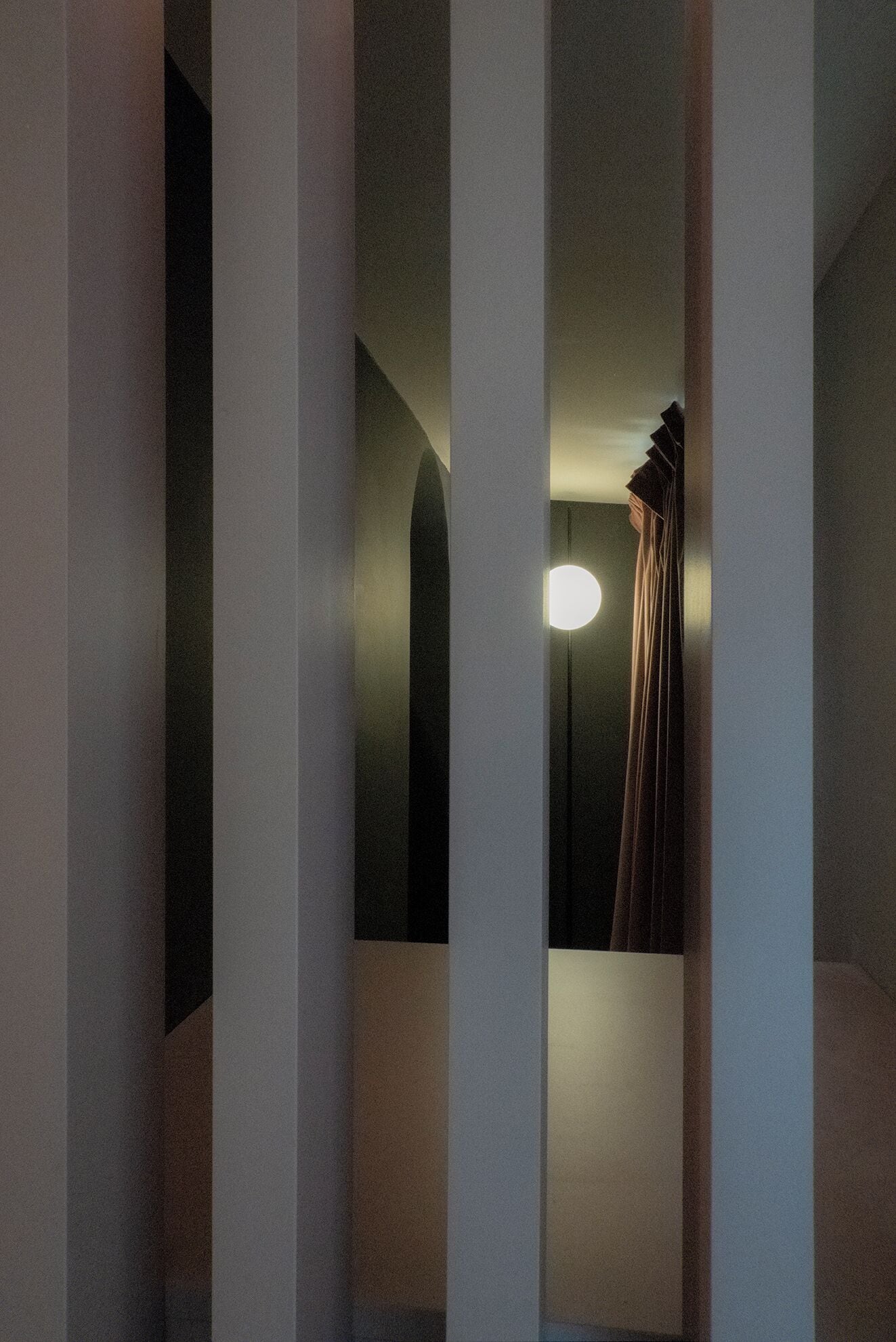 A narrow hallway with tall, evenly spaced columns and a single light fixture on the ceiling.