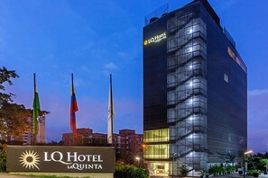 The exterior of the LQ Hotel La Quinta with its modern glass facade and a signboard displaying the hotel name. - La Quinta by Wyndham Medellin (Medellín)