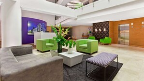 A modern lobby with green sofas, a white coffee table, and a large potted plant. - La Quinta by Wyndham Medellin (Medellín)