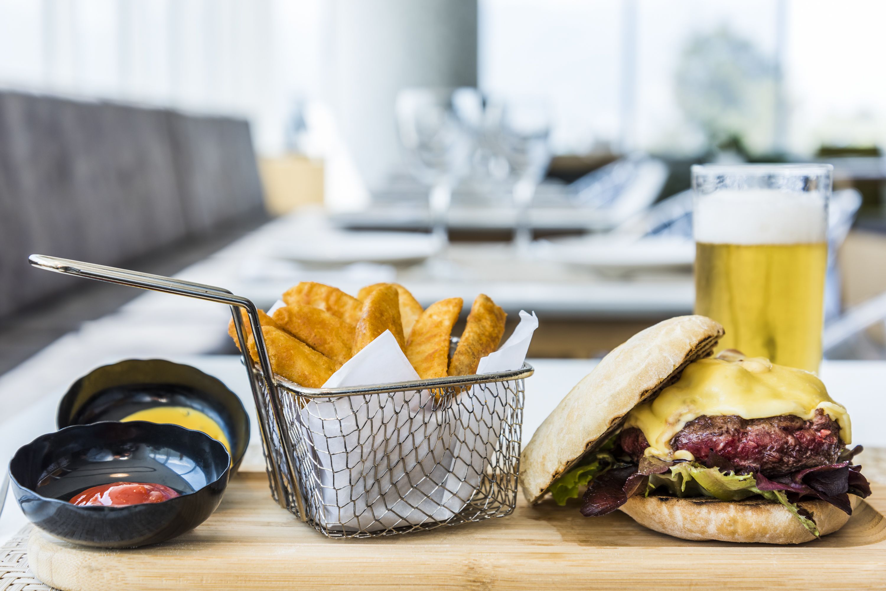 Un repas composé d’un sandwich, de frites et d’une bière, servis sur une table en bois.