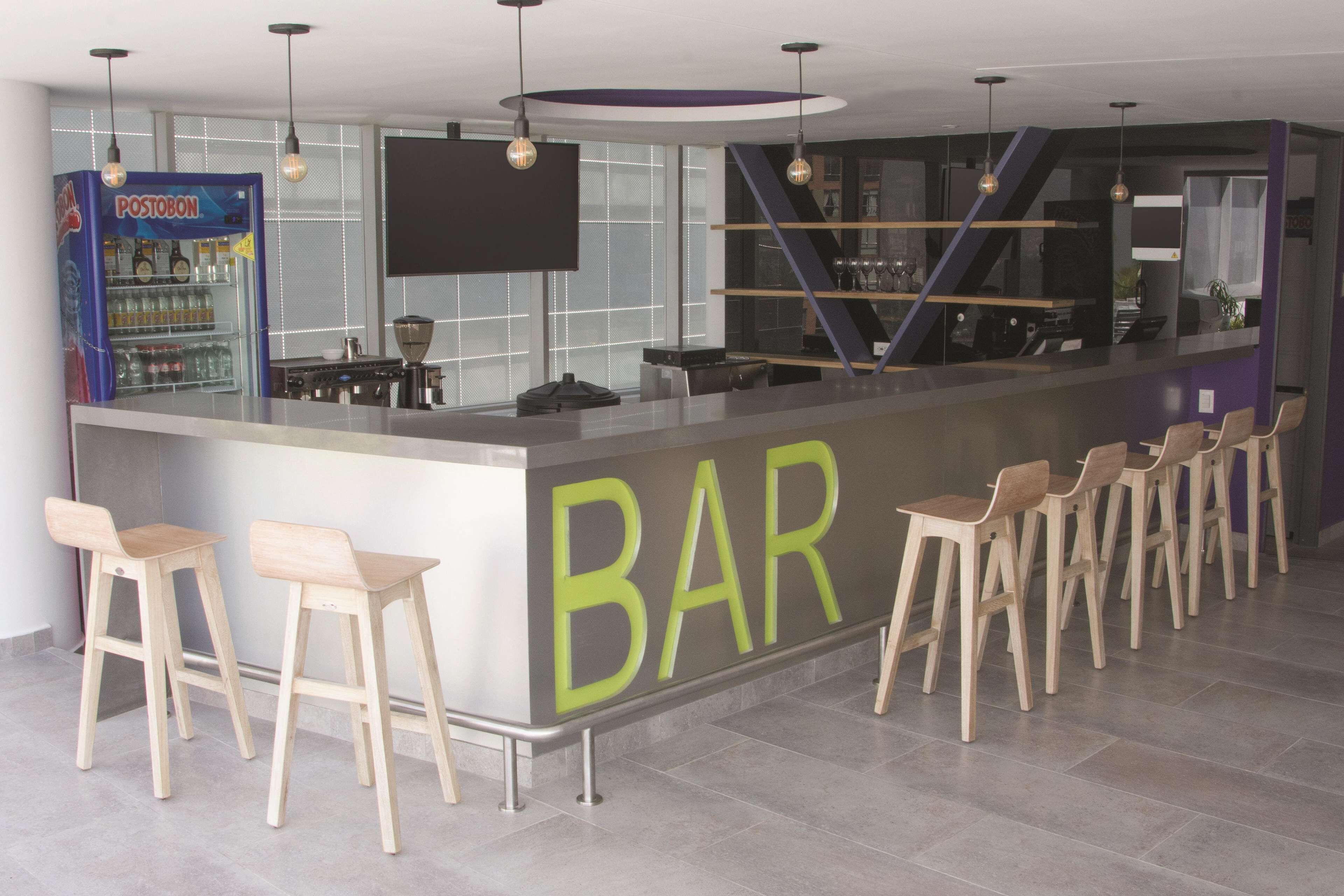 Un área de bar moderna con mostrador, taburetes y refrigerador.