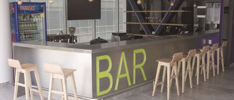 Un área de bar moderna con mostrador, taburetes y refrigerador.
