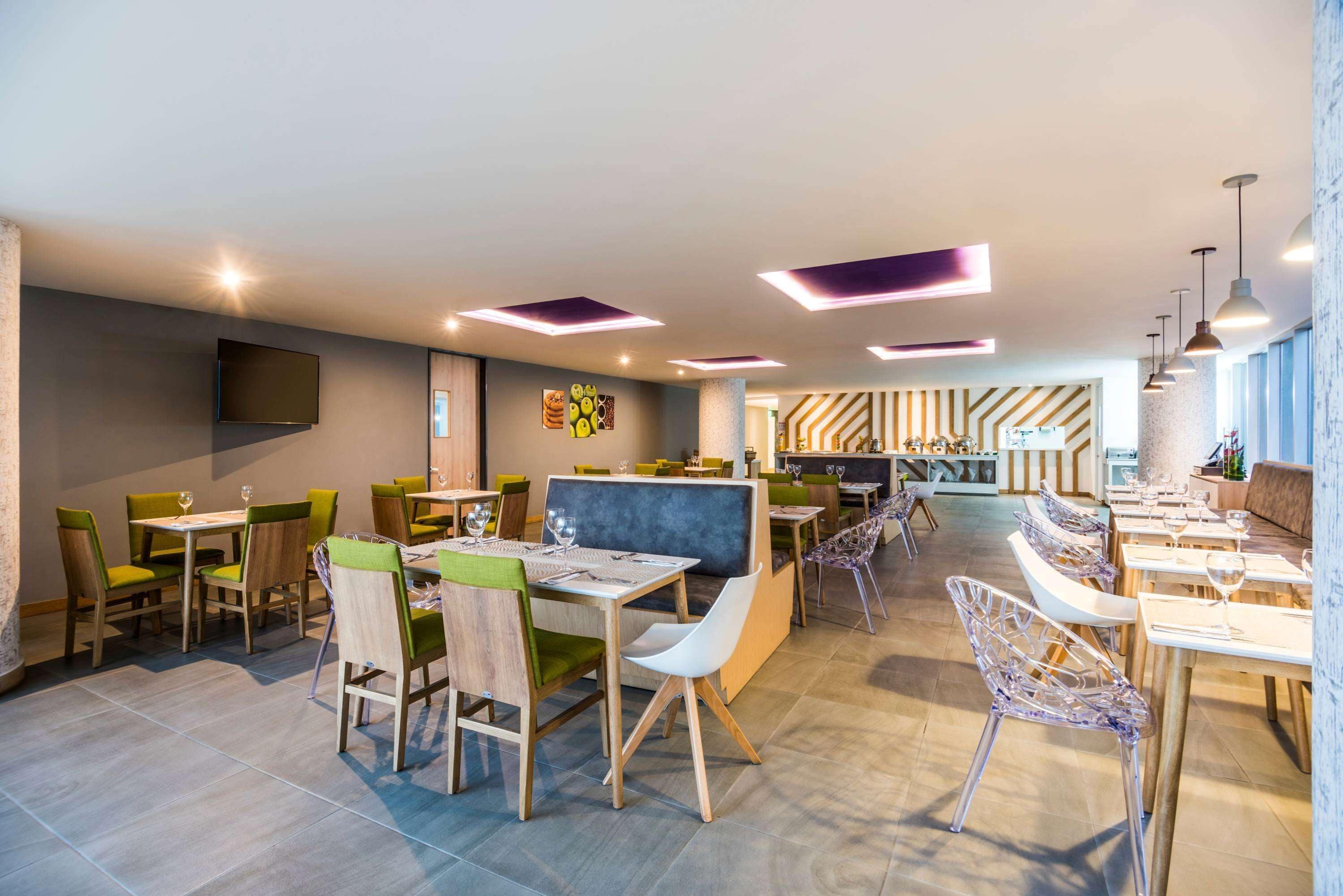 Un restaurant moderne doté de plusieurs espaces de restauration, notamment des banquettes et des tables avec des chaises.